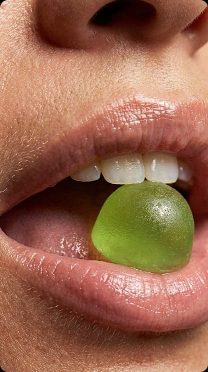 Close-up of a green gummy between someone's teeth